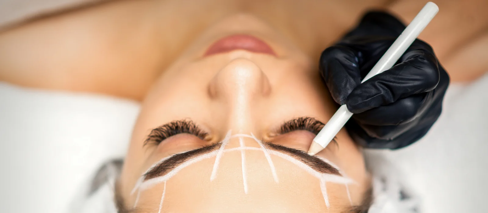 A certified artist mapping a client's eyebrow shape with a pencil before microblading at SpaRx Medical Aesthetics in Thonotosassa, FL
